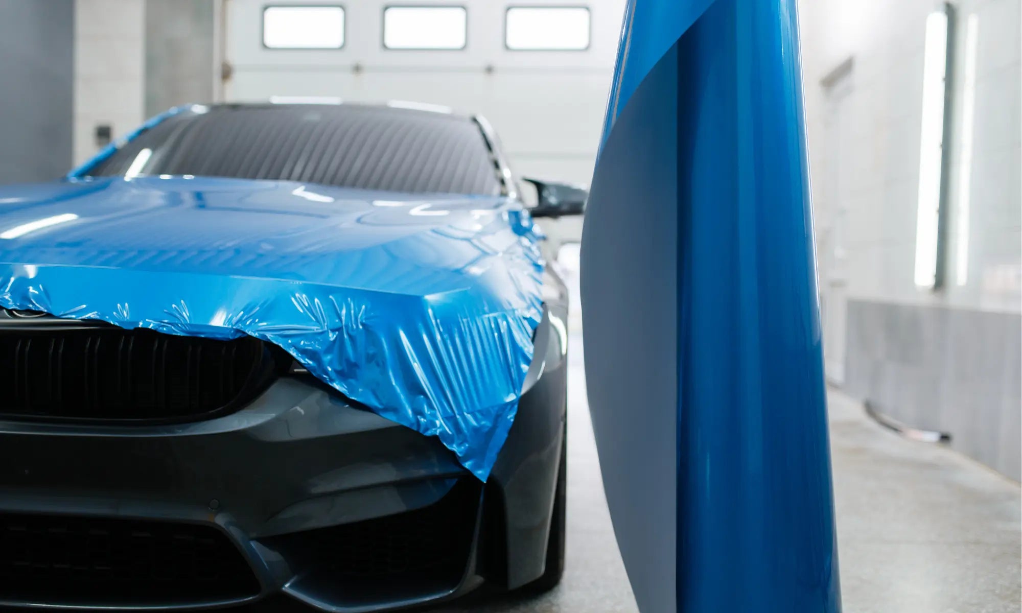 Pose d'un film adhésif de covering sur la carrosserie d'une voiture